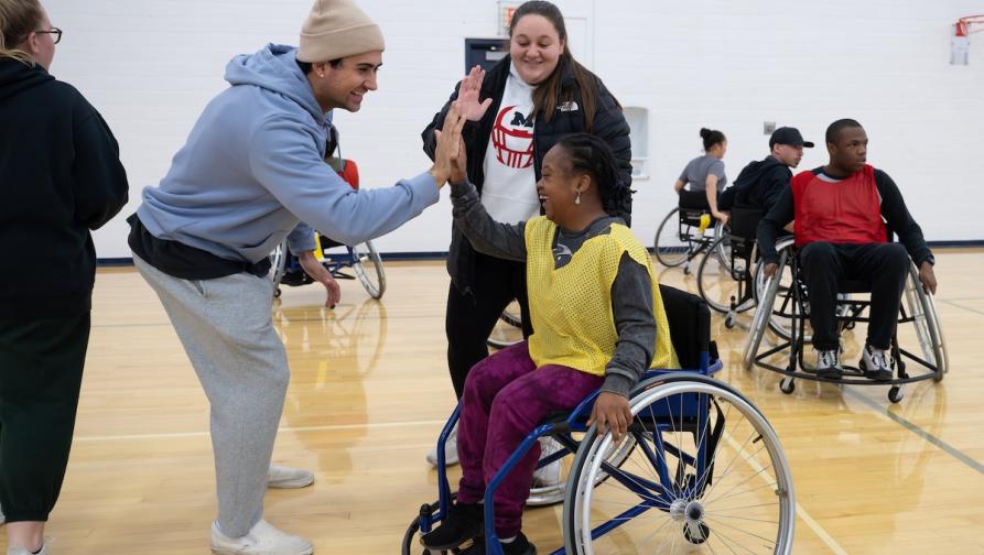 Man high fiving a woman in a wheelchair