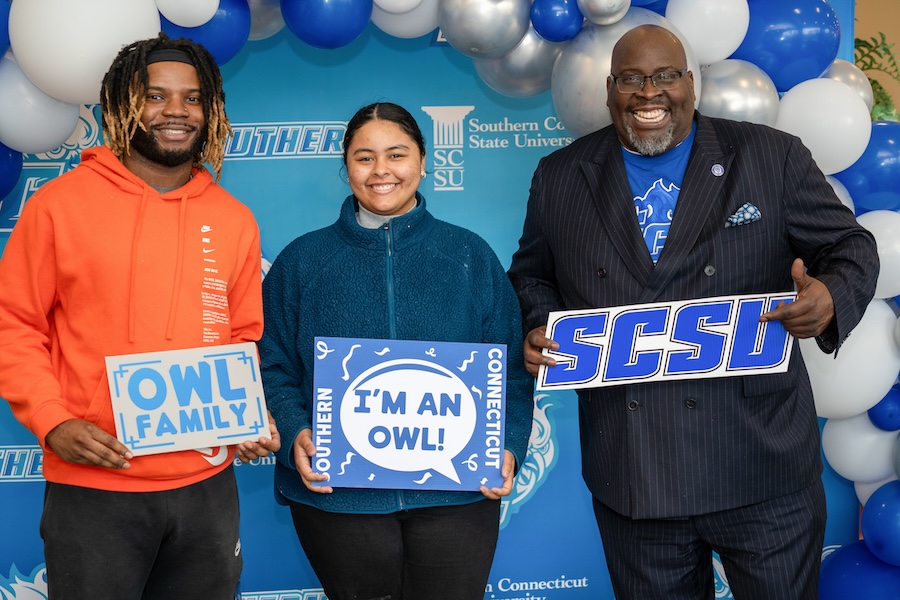 Dr. Dwayne Smith with two students holding SCSU signs