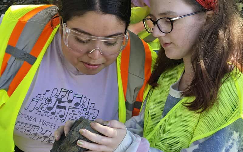 two students look closely at a rock sample