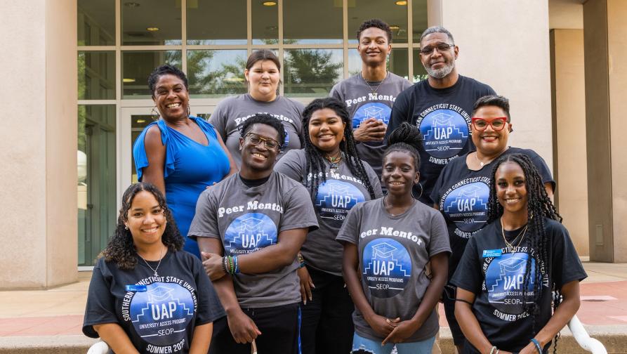 Director of University Access Programs, Dawn Stanton, and students part of the UAP program, smile on the steps outside of the Adanti Student Center.