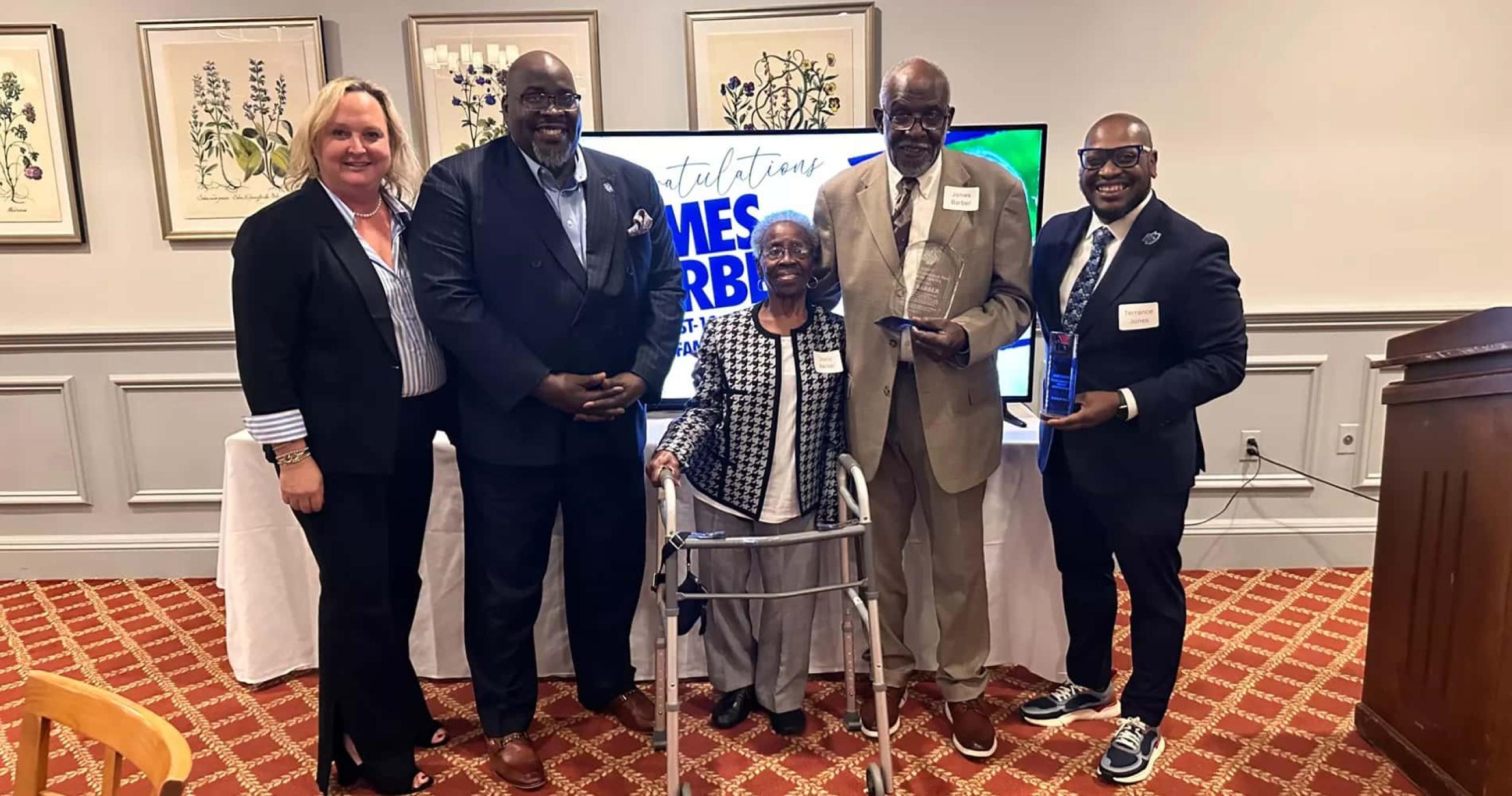 James Barber with NE10 Commissioner Julie Ruppert, SCSU Interim President Dwayne Smith, Mrs. Barber, and SCSU Director of Athletics Terrance Jones, after accepting his award