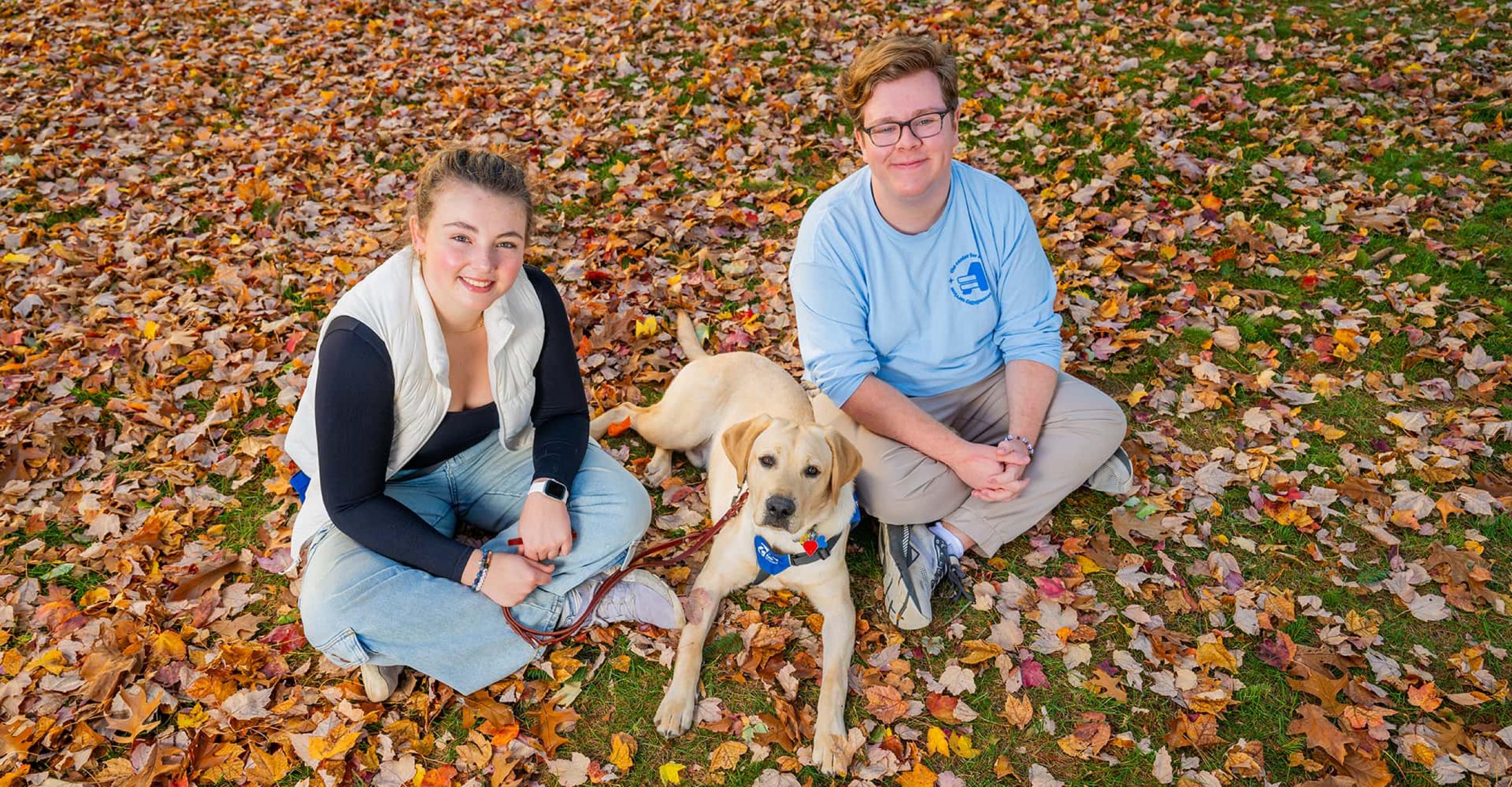 Ella Bernegger, founder and president of Guiding Eyes Puppy Raising at SCSU (right), and Cole Brown, executive board member of Guiding Eyes Puppy Raising at SCSU, with Justice -- a service dog in training